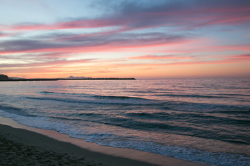 Romantischer Sonnenuntergang und Abendrot in rosa und rot an der Küste Kretas.