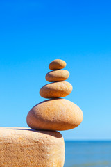 Rock zen pyramid of white stones on a background of blue sky and sea.