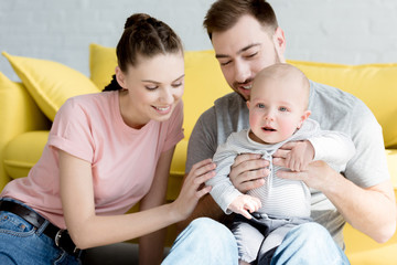 smiling parents with son sitting on yellow sofa