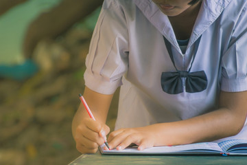Female student write a notebook for graduates in secondary schoo