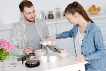 young couple having breakfast with corn flakes and coffee