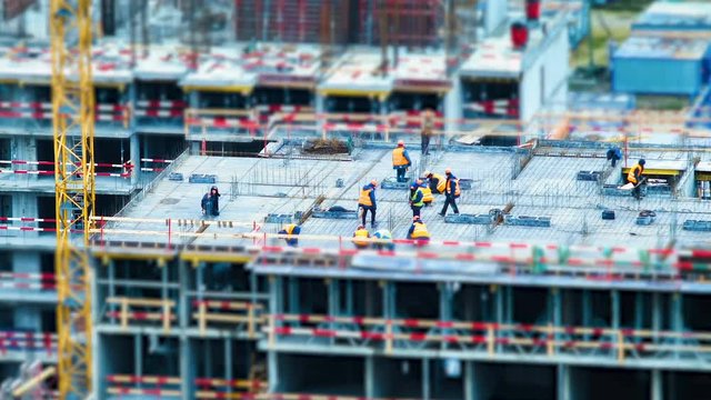 Time lapse tilt shift builders and cranes working on the construction site close up, zoom
