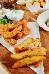 Delicious crispy fish with chips and sauce on wooden plate