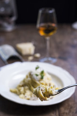 Tenedor con pasta y queso con una copa de vino