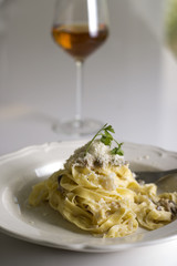 Plato de pasta con queso y una copa de vino