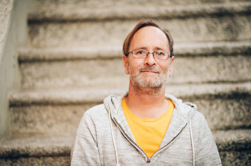 Outdoor portrait of 50 year old man wearing grey hoody and eyeglasses