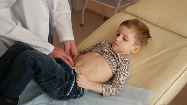 Doctor examination of the boy, abdomen probes. healthy patient on sunbed, search of hernia