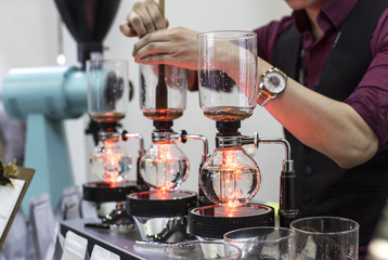 coffee preparation step by step. extraction process. Barista is pouring siphon into the flask from the kettle of hot water