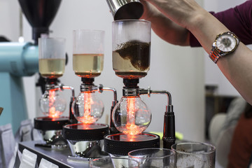 coffee preparation step by step. extraction process. Barista is pouring siphon into the flask from the kettle of hot water