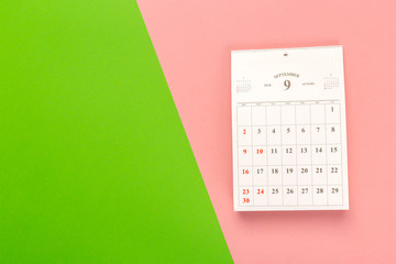 Calendar page on bright bicolor background, top view