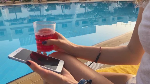 Girl using cellphone near the swimming pool.