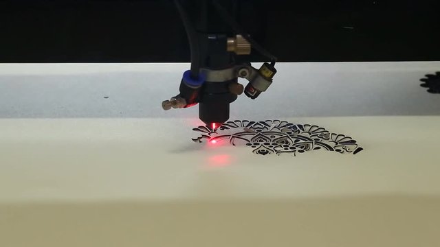 High precision CNC laser at work. Beam of laser cut out tracery from carton board. Modern technologies allow to receive high-precision parts. 