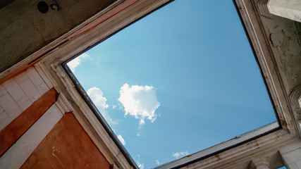 Bottom view of blue sky and clouds through the roof of old abandoned building