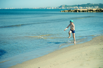 Fototapeta na wymiar Little boy is running along the beach