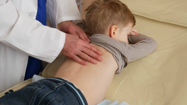 doctor examinate back of little boy close up