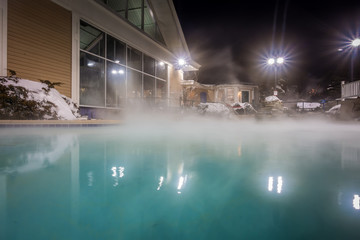 hot tubs and ingound heated pool at a mountain village in winter at night