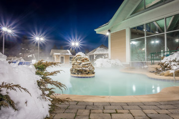 hot tubs and ingound heated pool at a mountain village in winter at night
