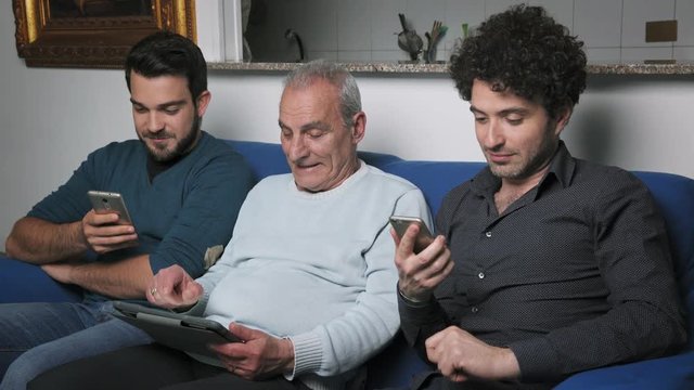frustrated old man using the tablet is helped by his sons
