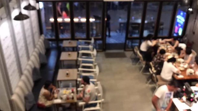 Time lapse blurred or defocused of customer enjoy eating and drink in coffee shop on top view. Group of people are sitting in modern cafe.