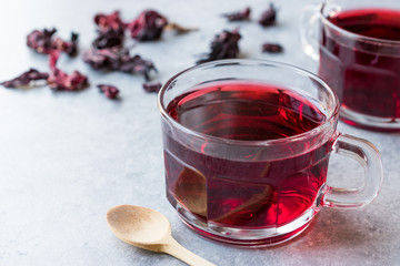 Red Hot Hibiscus Tea in a Glass Mug with Dry Hibiscus Tea Leaves.