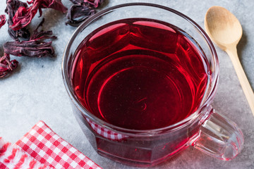 Red Hot Hibiscus Tea in a Glass Mug with Dry Hibiscus Tea Leaves.