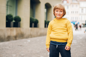 Obraz premium Outdoor portrait of handsome little boy in a city, wearing yellow hoody