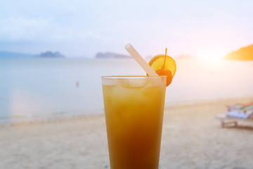 Fresh orange juice at the beach, Glass of orange juice on the sandy beach with sea in background