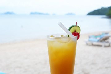 Fresh orange juice at the beach, Glass of orange juice on the sandy beach with sea in background