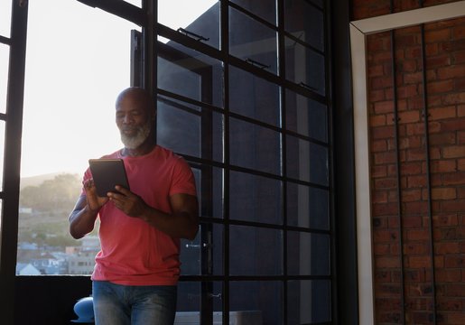 Senior man using digital tablet while standing at home