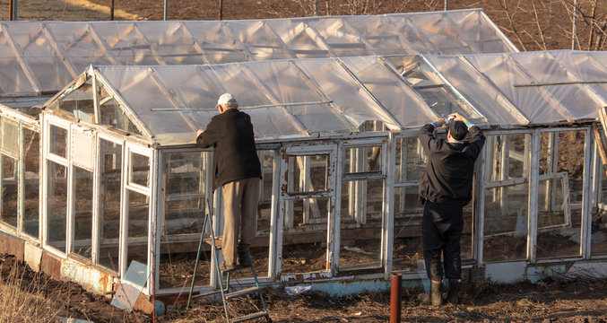 A man builds a greenhouse in the country