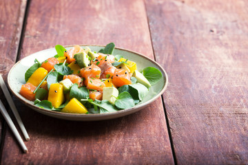Hawaiian Poke salad with salmon, avocado and vegetables on the plate on a rustic background