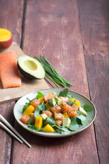 Hawaiian Poke salad with salmon, avocado and vegetables on a rustic background with copy space and vegetables on the background