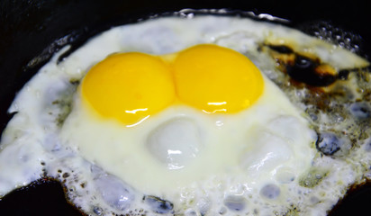 Fried one egg with two yolks. Strange phenomenon. Breakfast in a cast iron pan.