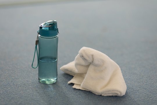 Sipper water bottle and towel on the floor of the gym