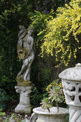 Obraz premium Marmorfigur und Steinlampe mit Ginster im Garten