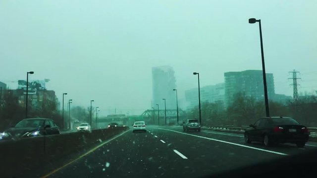 Passenger POV looking out wintry car windshield as car travels on DVP under various overpasses