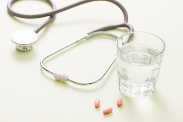 colored pills and a glass of water and stethoscope