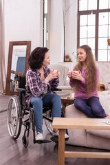 Face to face. Attractive handicapped woman and girl communicating while drinking tea