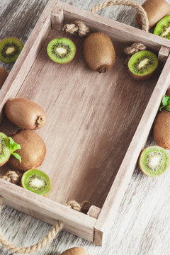 Green kiwis and mint leaves in the wooden tray