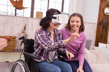 Virtual reality. Glad disabled woman wearing VR glasses while girl laughing