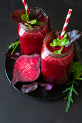 Fresh beetroot smoothie, beet, arugula and lettuce leaves on dark wooden background