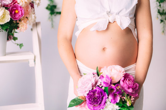 Naked belly of pregnant women.With flowers.Close-up view