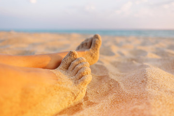 Fototapeta na wymiar Close-up view of female barefoot legs on sand.