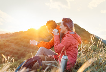 Happy traveler couple resting in the mountains at sunset. - 203227895