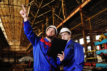 Two industrial workers in construction helmets discuss the project