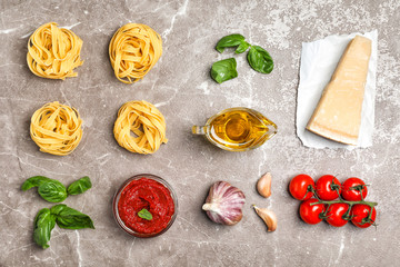 Flat lay composition with raw pasta and ingredients for sauce on table