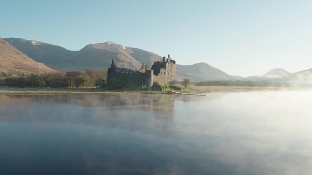 Incredible aerial drone shot of Kilchurn Castle with low mist, Scotland
