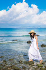 Fototapeta na wymiar woman traveler enjoying for view of the sea on her holiday.beautiful Asia Lady tourist in white dress and rise walking on the beach.