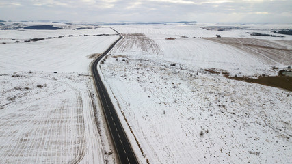 View from the air on the winter road in the field on which cars are going