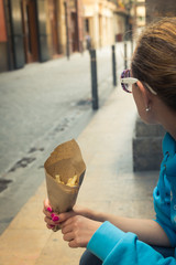 A girl holding french fries in hand in the street